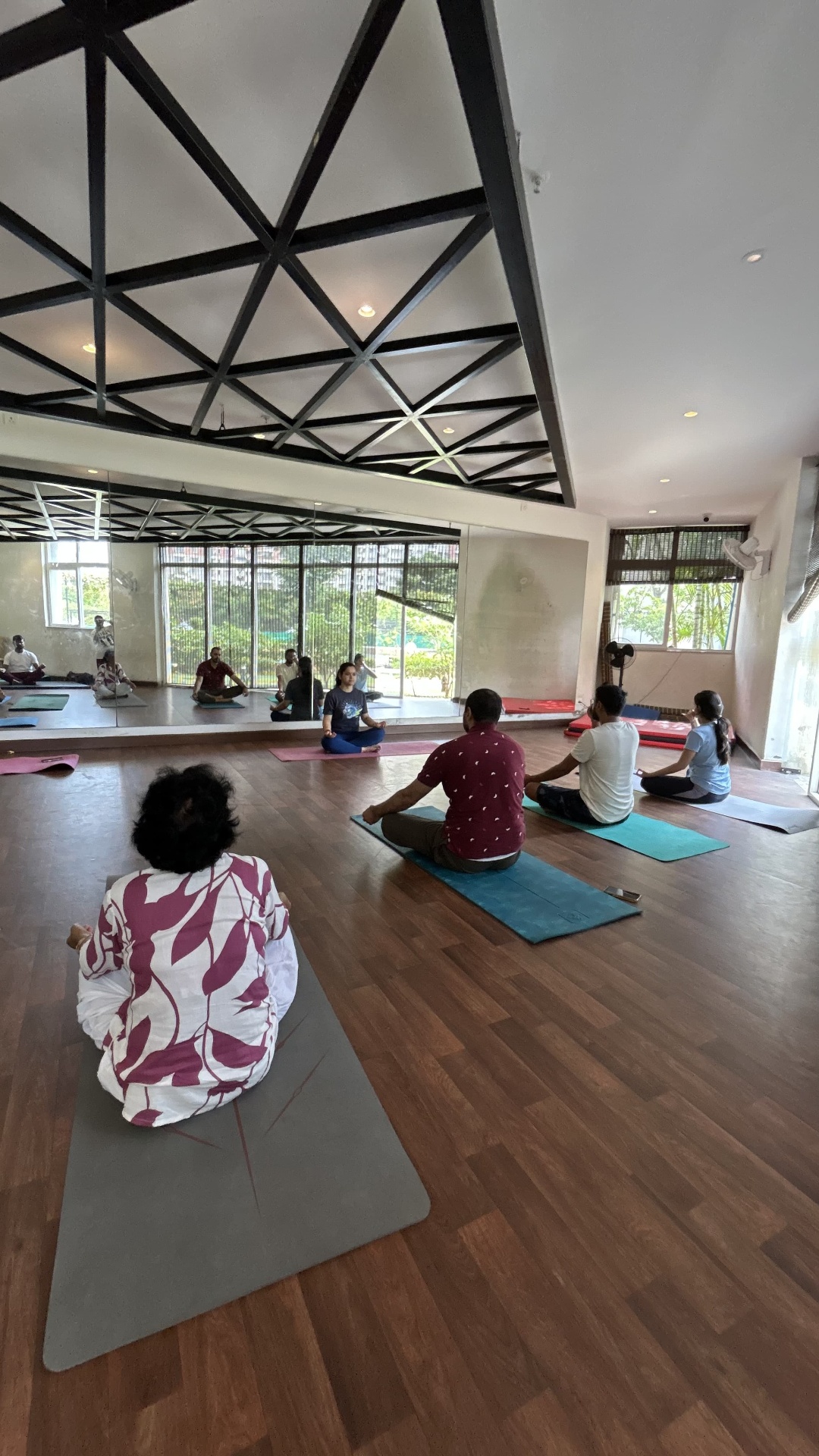 Seated practice with the group in a mirrored, sunlit studio