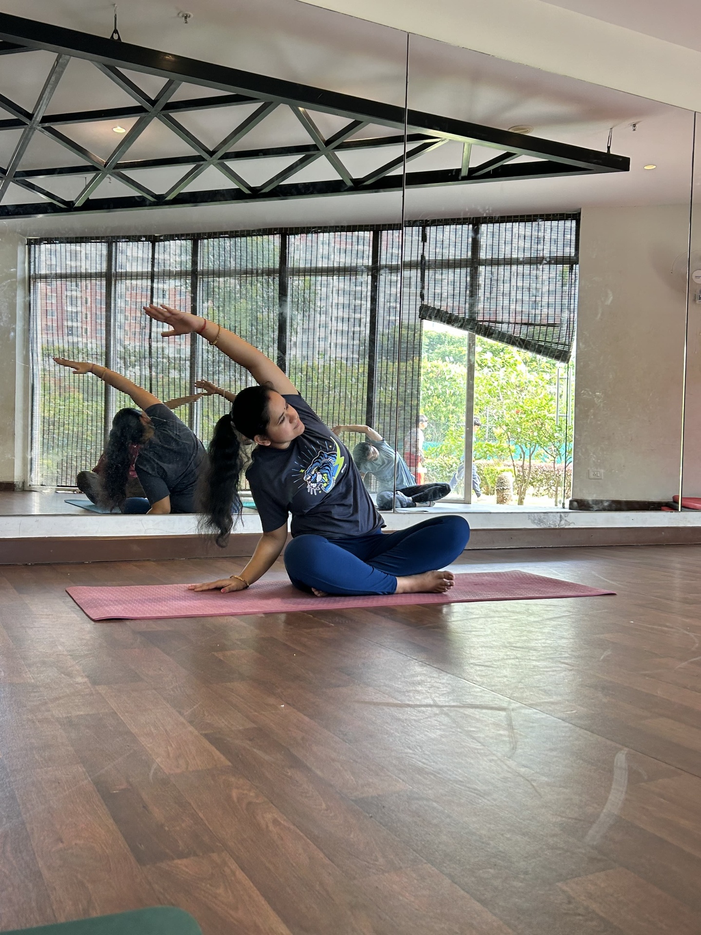 Priyamvada in a seated side bend, arm extended overhead